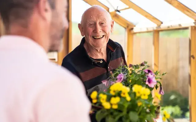 A carer and resident with flowers
